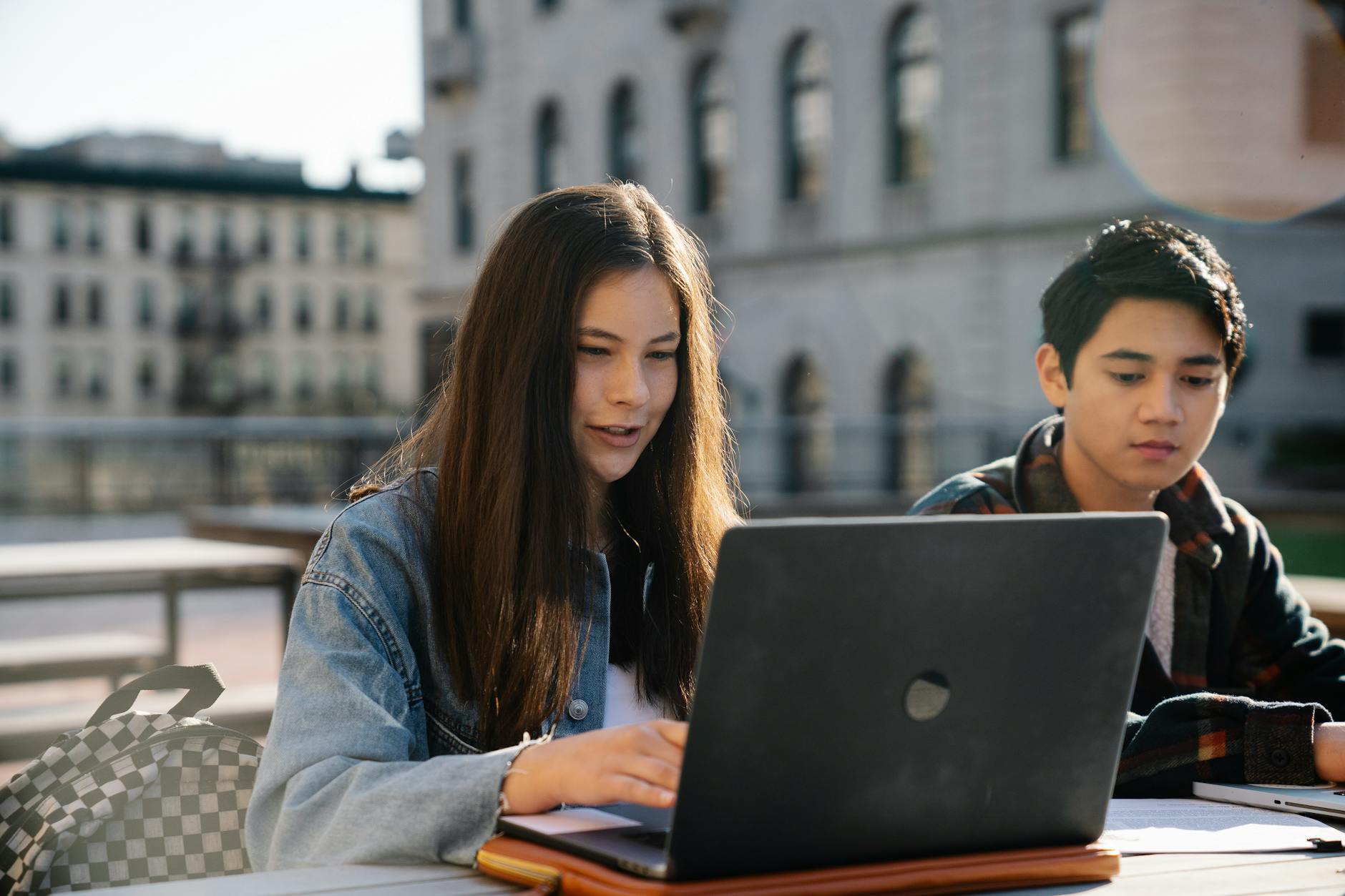 Dwójka studentów uczy się przy laptopie przed zabytkowym budynkiem