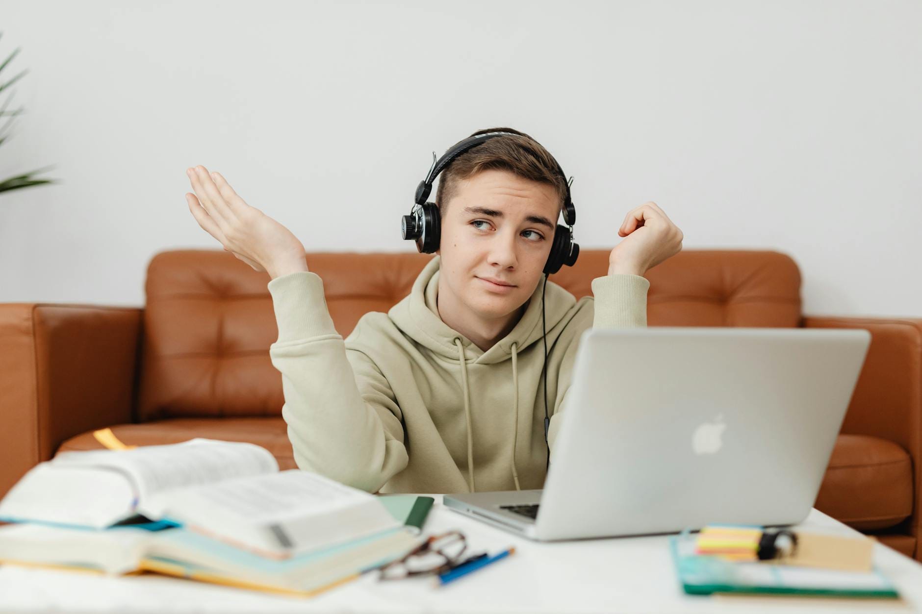 Młody mężczyzna w słuchawkach uczy się online na laptopie w domu